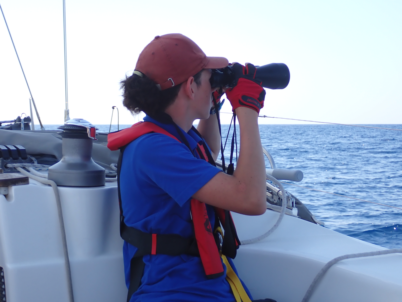 Юный яхтсмен с биноклем смотрит горизонт